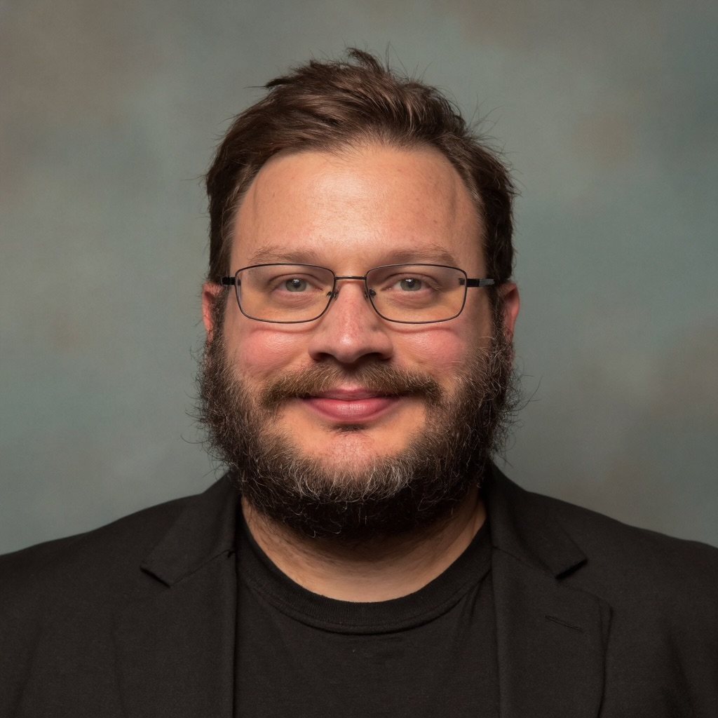 Tyler Whitney wearing glasses and a black blazer